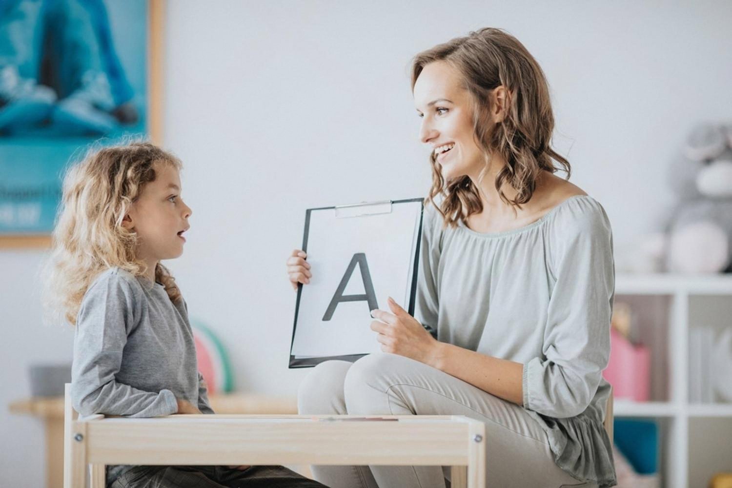 Teacher showing a child a printed letter A during a spoken language lesson