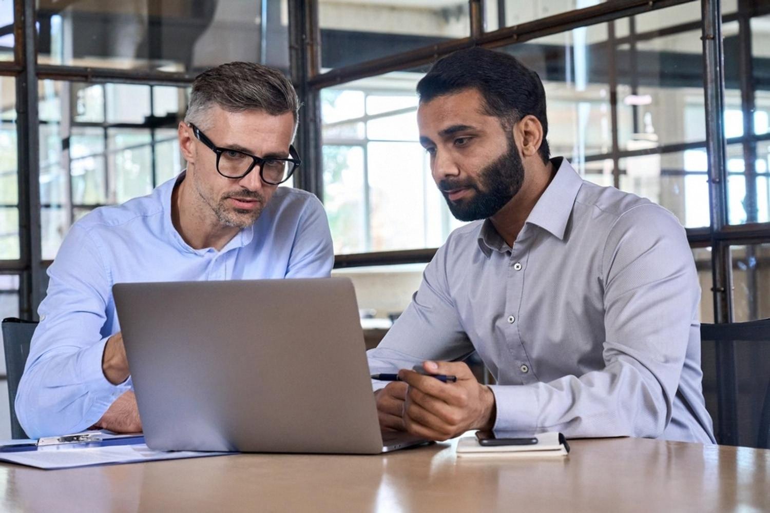 Two consultants examining company records on a laptop during a background check in the UAE