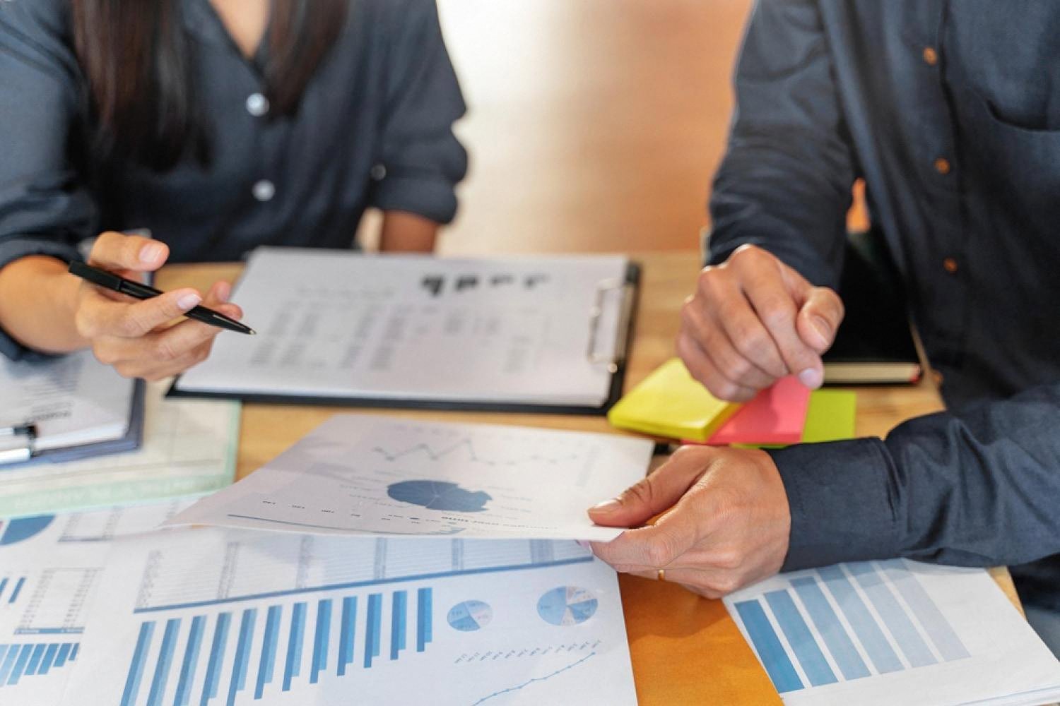 Two professionals reviewing financial statements and charts before signing a UAE business deal